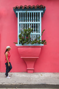 Full length of boy standing on sidewalk against wall