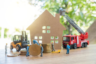 Close-up of figurines by model house on wooden table