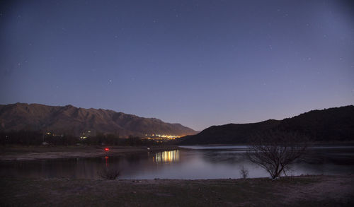 Scenic view of lake by mountains against star field