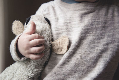 Midsection of boy holding stuffed toy at home
