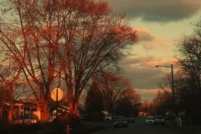 Cars on road against cloudy sky at sunset