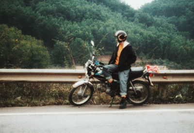Man with bicycle on road against trees