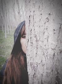 Portrait of a young woman standing on tree trunk