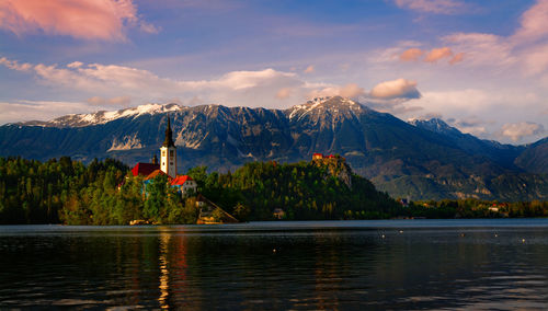 Scenic view of lake by mountains against sky during sunset