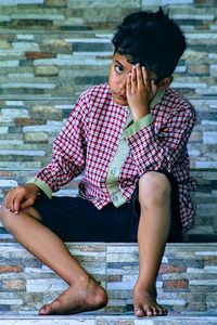 Young man looking away while sitting outdoors