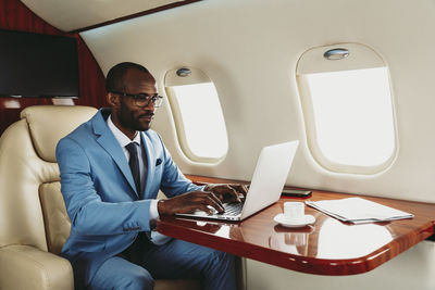 Young businessman concentrating while working on laptop in private jet