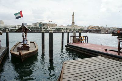 Boats moored on river in city against sky