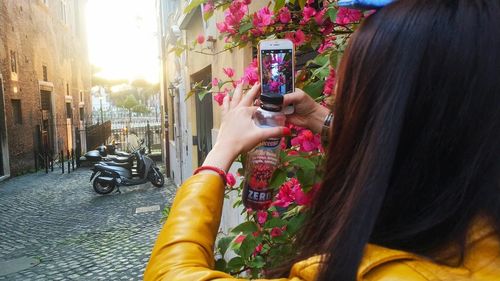 Portrait of woman photographing with mobile phone while standing on street