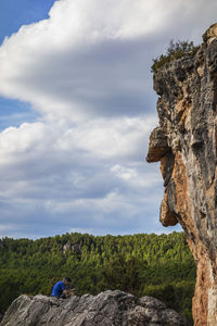 Man climbing rock on mountain against sky