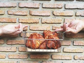 Cropped hands of people holding croissants in basket