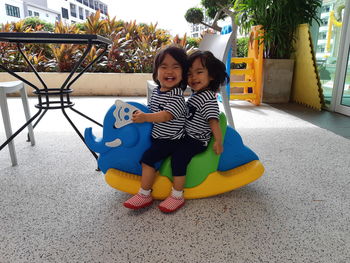 Portrait of twins sitting on toy