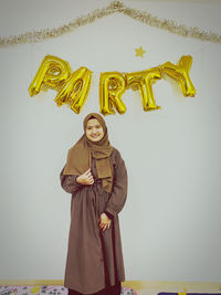 Young woman standing against yellow wall