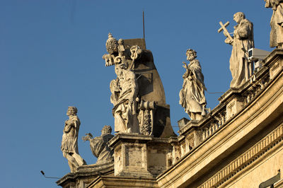 Low angle view of statues on st peter basilica against clear blue sky