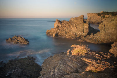 Rocks on shore by sea against sky