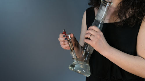 Midsection of woman smoking hookah against white background