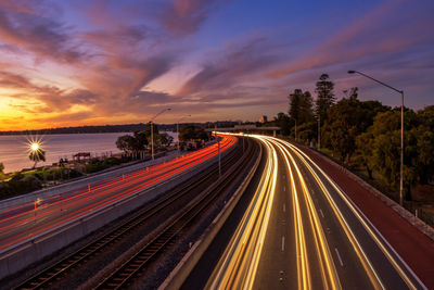 Light trails on road against sky during sunset