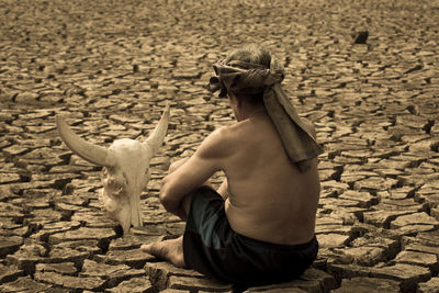 Man sitting on cracked ground