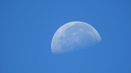 Low angle view of moon against clear blue sky