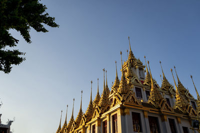 Low angle shot of thailand wat with golden roof and beautiful architecture under blue sky.