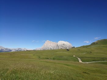 Scenic view of field and mountains against clear blue sky