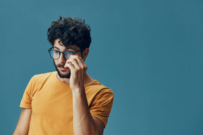 Young man using mobile phone against clear blue sky