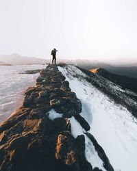 Side view of person photographing on snowcapped mountain