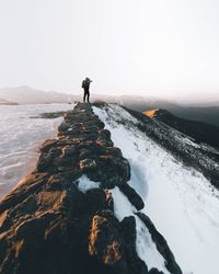 Rear view of man walking on snow covered mountain