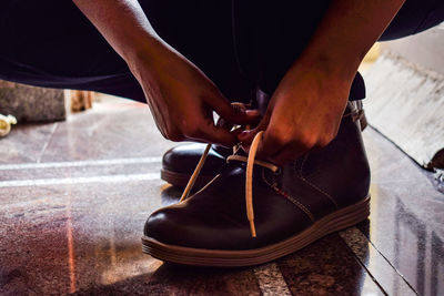 Low section of person tying shoe on floor