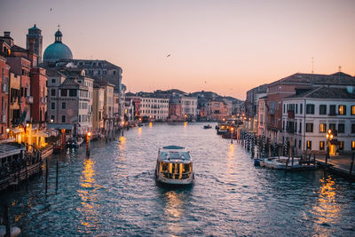 Canal amidst buildings against sky during sunset