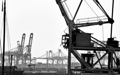 Cranes at commercial dock against clear sky