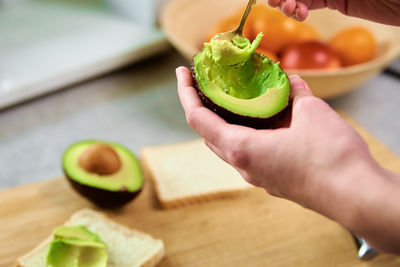 Woman hold fresh ripe avocado and peeling it with spoon, healthy food and dieting concept