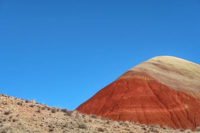 Low angle landscape of barren orange and tan hillside at the painted hills in oregon