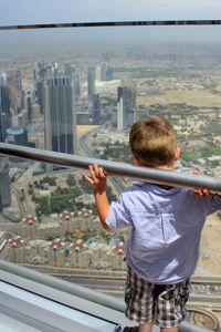 Rear view of boy looking at cityscape while standing in burj khalifa