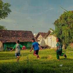 Rear view of children on field against sky