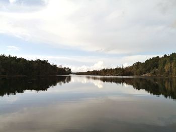 Scenic view of lake by trees against sky