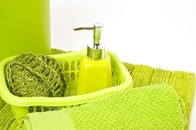 Close-up of soap dispenser with towel and basket over white background