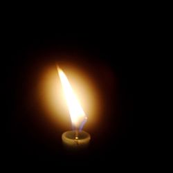 Close-up of lit candle in darkroom