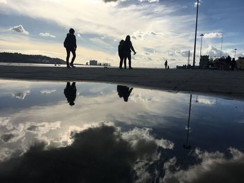 Silhouette people on lake against sky