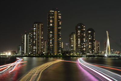 High angle view of light trails on river against illuminated city