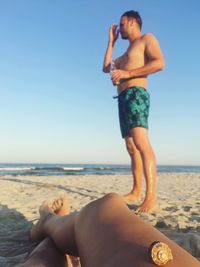 Low section of woman on beach against clear sky