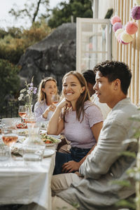 Smiling young man sitting with male friends celebrating dinner party at cafe