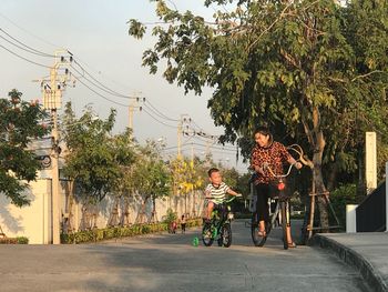 Children riding bicycle against trees in city