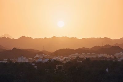 Sun above old city against mountain range. nizwa in sultanate of oman at amazing sunset.