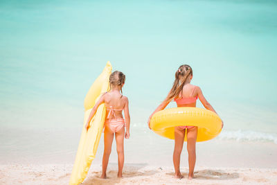 Rear view of sisters standing on beach