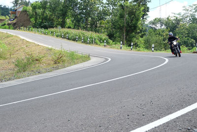 Rear view of man riding bicycle on road