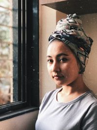 Close-up portrait of young woman standing at window