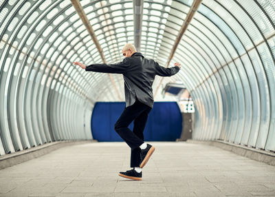 Full length of man dancing on a footpath in tunnel