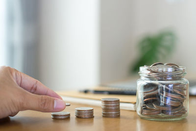 Close-up of hand holding glass of jar on table