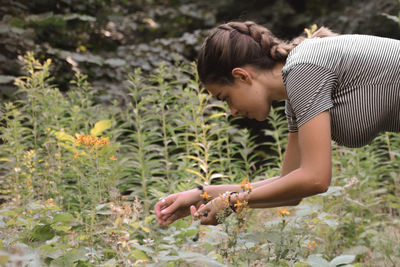 Profile of young woman picks ripe raspberries