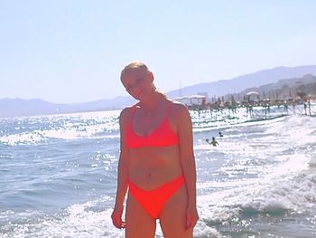 Woman standing at beach against sky